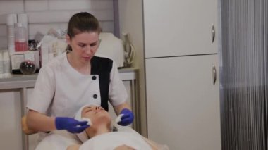 Profesyonel güzellik uzmanı ıslak mendille kadının yüzünü siler..