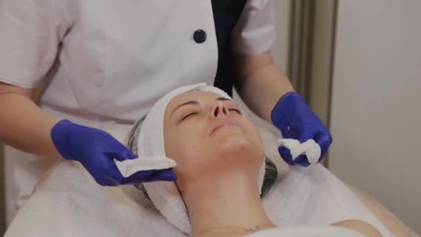 Esteticista profesional limpia la cara de la mujer con toallitas húmedas . — Vídeos de Stock