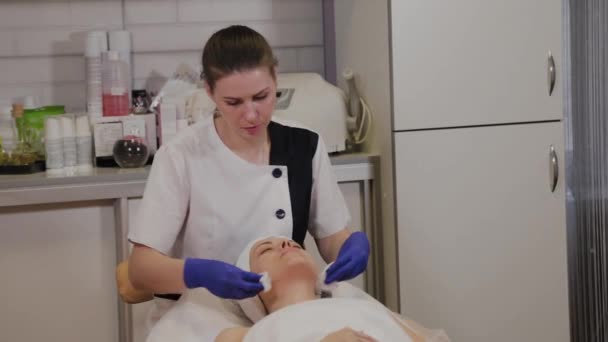 전문적 인 미용사가 젖은 휘일 체어 로 여인의 얼굴을 닦는다. — 비디오