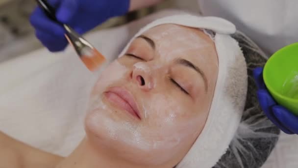 Profissional aplica uma máscara facial a uma mulher com uma escova . — Vídeo de Stock