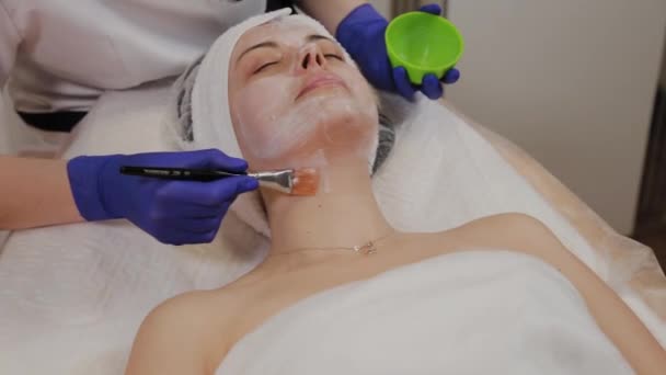 Profissional aplica uma máscara facial a uma mulher com uma escova . — Vídeo de Stock