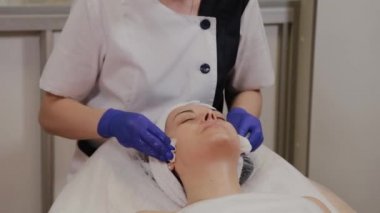 Profesyonel güzellik uzmanı ıslak mendille kadının yüzünü siler..