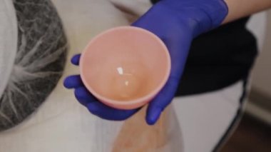 Profesyonel güzellik uzmanı bir kaseye yüz serumu döker..