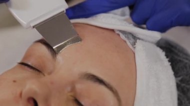 Profesyonel güzellik uzmanı orta yaşlı bir kadın için ultrasonik yüz temizliği yapıyor..