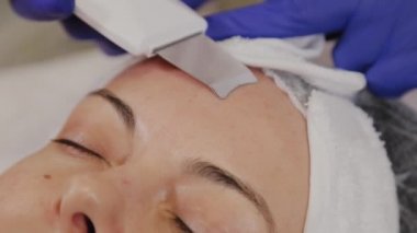 Profesyonel güzellik uzmanı orta yaşlı bir kadın için ultrasonik yüz temizliği yapıyor..