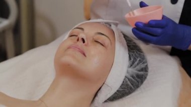 Profesyonel güzellik uzmanı yüz serumunu fırçayla uyguluyor.