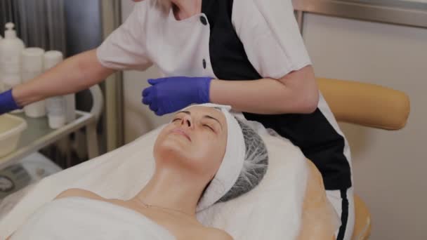 プロの美容師は、ウェットワイプで女性の顔を拭く. — ストック動画