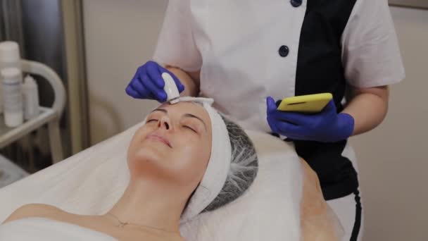 En professionell kosmetolog mäter hudens tillstånd med hjälp av ett instrument. — Stockvideo
