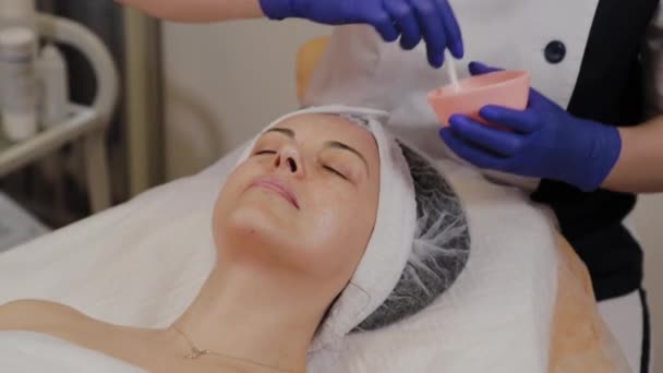 Esteticista profissional aplica soro de cara com uma escova . — Vídeo de Stock