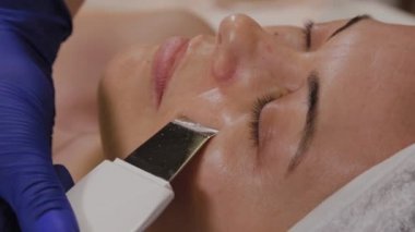 Profesyonel güzellik uzmanı orta yaşlı bir kadın için ultrasonik yüz temizliği yapıyor..