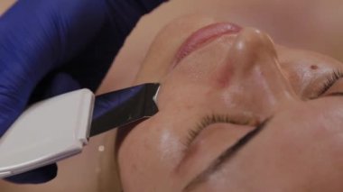 Profesyonel güzellik uzmanı orta yaşlı bir kadın için ultrasonik yüz temizliği yapıyor..