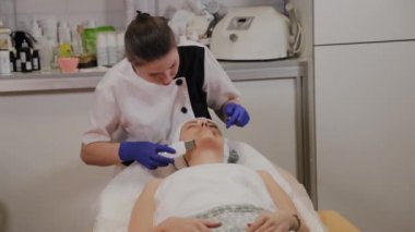 Profesyonel güzellik uzmanı orta yaşlı bir kadın için ultrasonik yüz temizliği yapıyor..