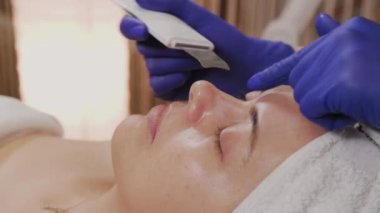 Profesyonel güzellik uzmanı orta yaşlı bir kadın için ultrasonik yüz temizliği yapıyor..