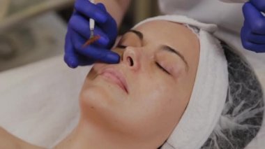Profesyonel güzellik uzmanı orta yaşlı bir kadın için ultrasonik yüz temizliği yapıyor..