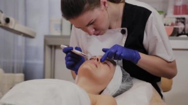 Profesyonel güzellik uzmanı orta yaşlı bir kadın için ultrasonik yüz temizliği yapıyor..