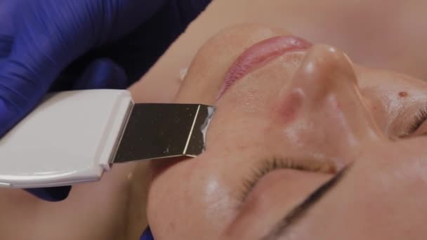 Professional beautician does ultrasonic face cleaning for middle-aged woman. — Stock Video