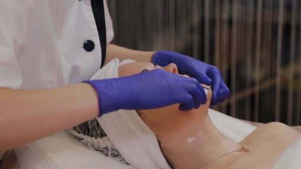 Professionell kosmetolog gör ultraljud ansikte rengöring för medelålders kvinna. — Stockvideo