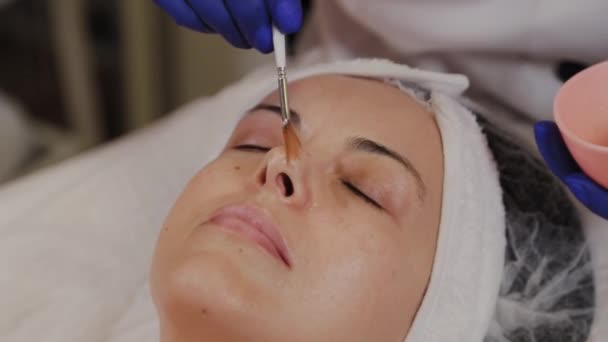 Esteticista profissional aplica soro de cara com uma escova . — Vídeo de Stock