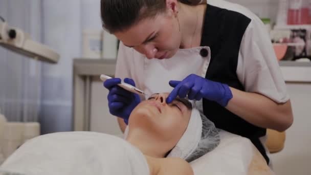 Professionele schoonheidsspecialiste doet ultrasone gezichtsreiniging voor vrouwen van middelbare leeftijd. — Stockvideo