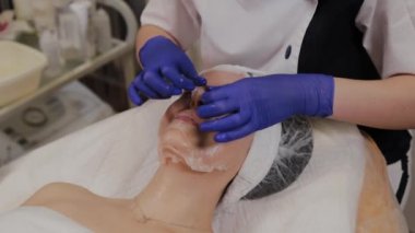 Profesyonel bir güzellik uzmanı yüzüne şeffaf bir yüz maskesi takar..