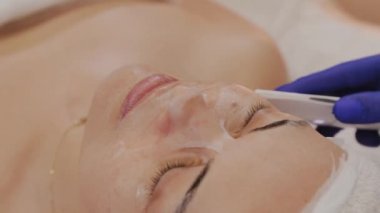 Profesyonel güzellik uzmanı orta yaşlı bir kadın için ultrasonik yüz temizliği yapıyor..
