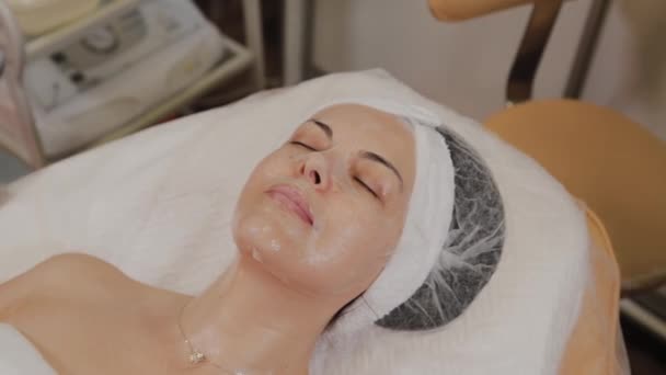 Un esthéticien professionnel applique un masque facial en tissu transparent sur le visage . — Video