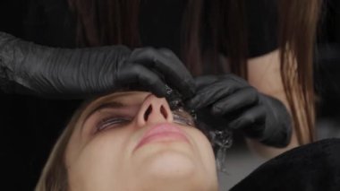 Bir güzellik salonundaki profesyonel güzellik uzmanı müşterisinin gözlerini özel bir filmle kapatır..