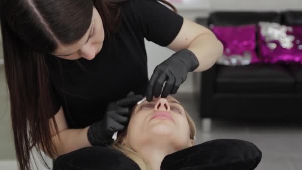 Un esteticista profesional en un salón de belleza realiza un procedimiento de laminación de pestañas . — Vídeos de Stock