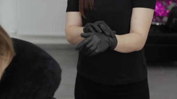 Professionele schoonheidsspecialiste in schoonheidssalon trekt handschoenen aan voor de ingreep. — Stockvideo