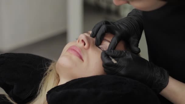 Professionelle Kosmetikerin in einem Schönheitssalon klebt Silikonfutter für Wimpernkaschierung. — Stockvideo