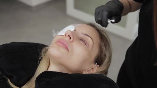Güzellik salonunda çalışan profesyonel bir kozmetikçi kirpik jelini müşterinin kirpiklerine sürer.. — Stok video