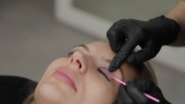 Esthéticienne professionnelle dans un salon de beauté redresse les cils d'un client . — Video