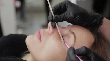 Güzellik salonundaki profesyonel güzellik uzmanı müşteriye kirpiklerini düzeltir..