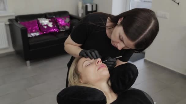 Een professionele schoonheidsspecialiste in een schoonheidssalon voert wimper lamineren procedure. — Stockvideo