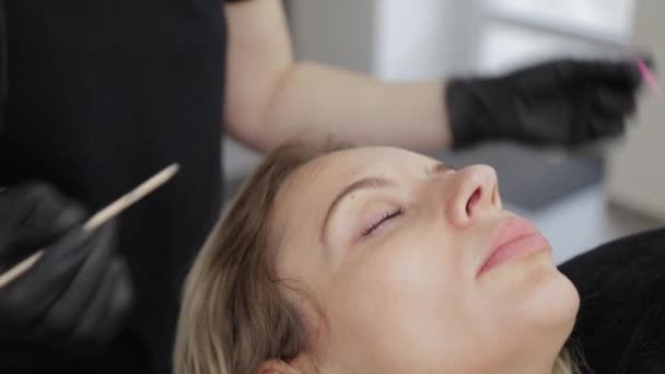 Professionell kosmetolog i en skönhetssalong rätar ut ögonfransarna till en kund. — Stockvideo
