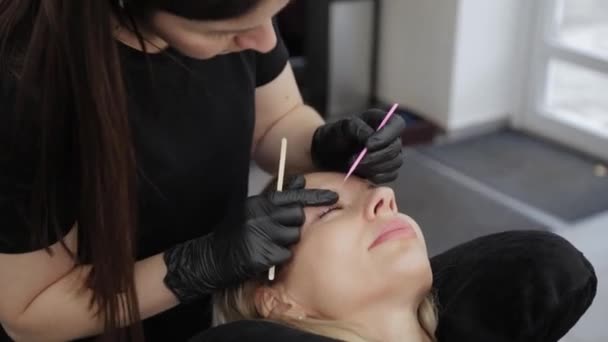 Professionelle Kosmetikerin in einem Schönheitssalon richtet einem Kunden die Wimpern. — Stockvideo