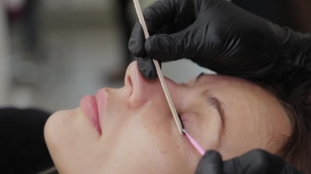Профессиональный косметолог в салоне красоты выпрямляет ресницы клиенту . — стоковое видео