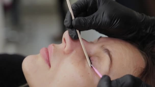 Professionelle Kosmetikerin in einem Schönheitssalon richtet einem Kunden die Wimpern. — Stockvideo