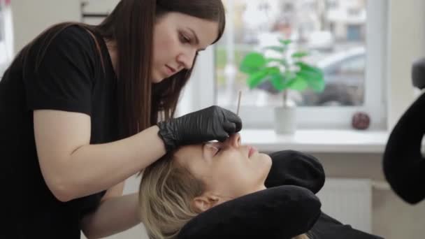 Professionele schoonheidsspecialiste in een schoonheidssalon recht wimpers naar een klant. — Stockvideo