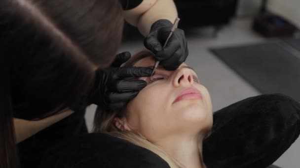 Un esthéticien professionnel dans un salon de beauté effectue une procédure de plastification des cils . — Video