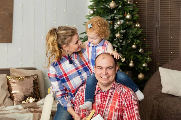 Happy family at the Christmas tree in the interior. New Year 2020.