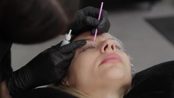 Ein professioneller Kosmetiker in einem Schönheitssalon trägt das Wimpernlaminierungsgel auf die Wimpern des Kunden auf. — Stockvideo