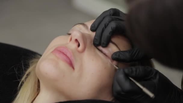 Eine professionelle Kosmetikerin in einem Schönheitssalon führt eine Wimpernlaminierung durch. — Stockvideo