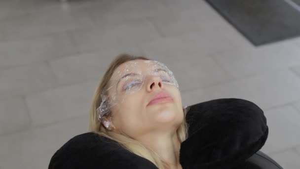 Belle femme avec un film sur les yeux dans un salon de beauté . — Video