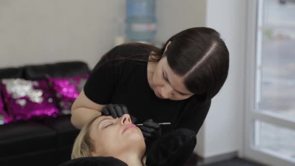 Un esthéticien professionnel dans un salon de beauté effectue une procédure de plastification des cils . — Video