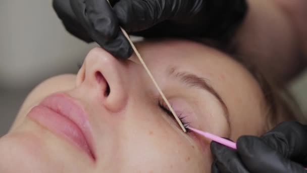Szakmai kozmetikus egy szépségszalonban kiegyenesíti a szempillákat egy ügyfélnek. — Stock videók