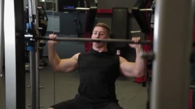 Profesyonel sporcu omuzlarını halterle eğitir..