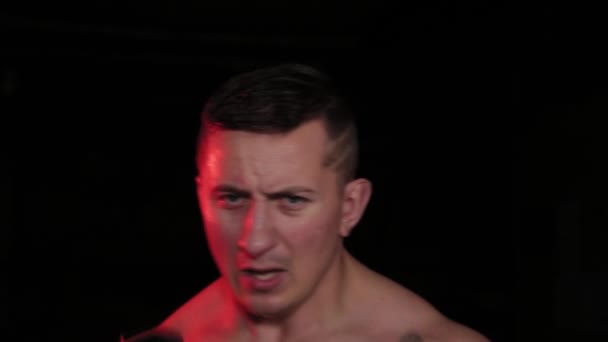 Atlétikai férfi boksz súlyzókkal piros világításban. — Stock videók