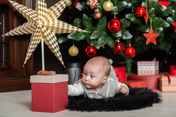 Menino bonito no chão pela árvore de Ano Novo . — Fotografia de Stock