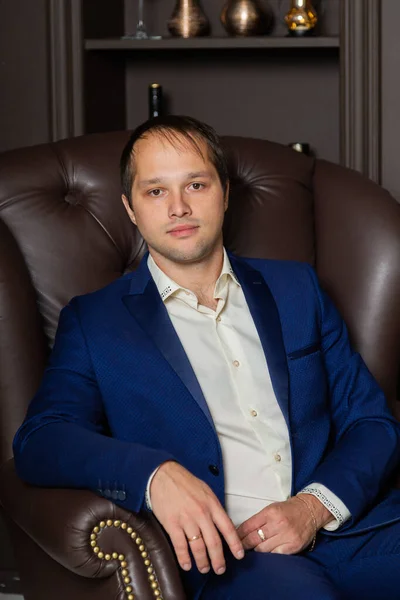 Hombre de negocios serio en un sillón de cuero e interior premium . — Foto de Stock